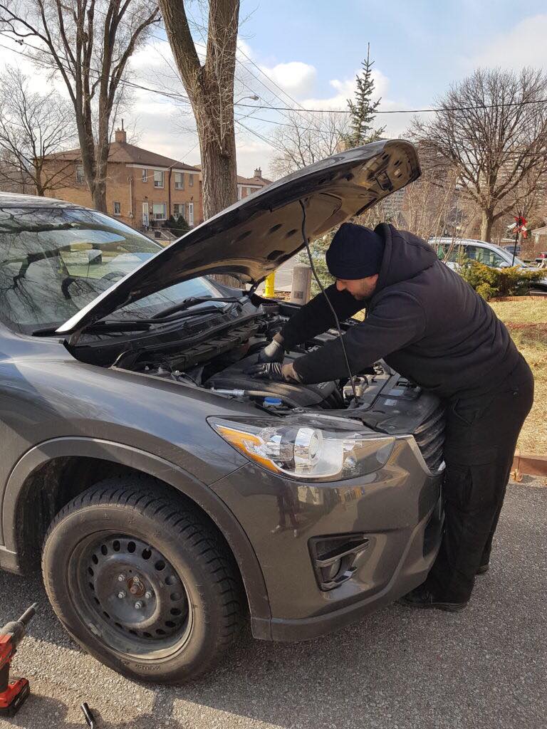 A Toronto Mobile Mechanic fixing the hood of a car